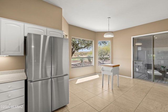 kitchen with white cabinetry, light tile patterned floors, decorative light fixtures, and stainless steel fridge