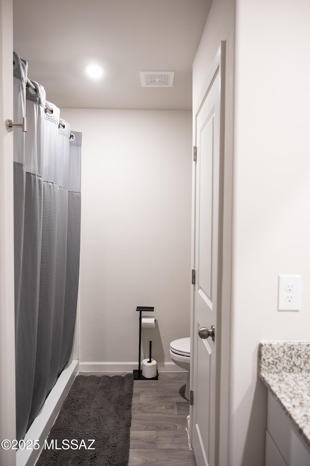 bathroom with baseboards, visible vents, toilet, wood finished floors, and vanity