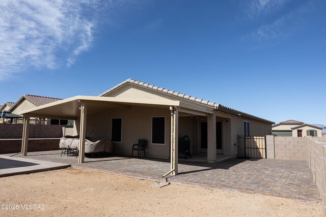 rear view of house featuring a fenced backyard, a patio, and stucco siding