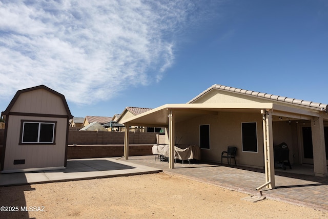 back of house with a patio area, fence, a storage unit, and an outbuilding