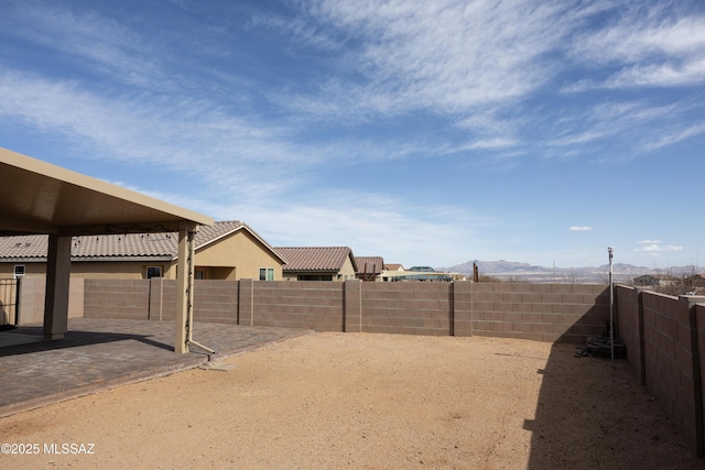 view of yard with a patio area, a fenced backyard, and a mountain view