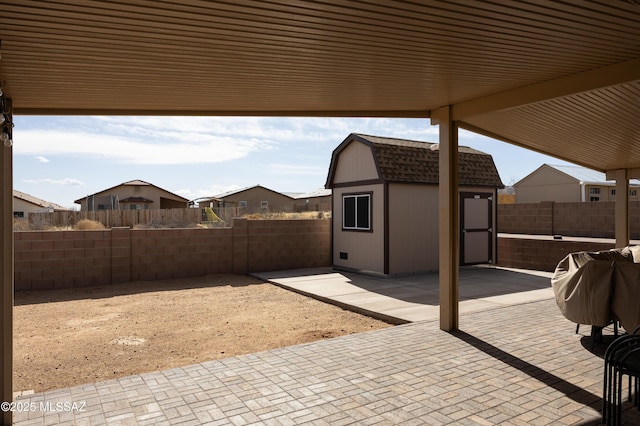 view of patio / terrace with an outbuilding, a storage shed, and a fenced backyard
