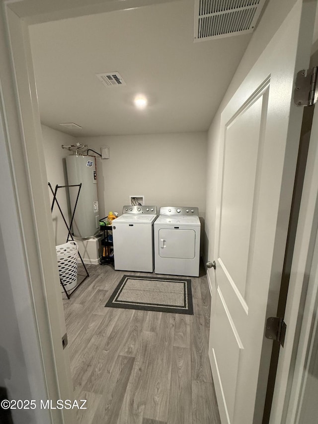 clothes washing area with laundry area, visible vents, wood finished floors, and independent washer and dryer