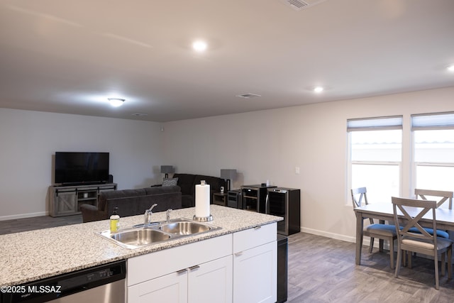 kitchen featuring dark hardwood / wood-style floors, sink, white cabinets, stainless steel dishwasher, and light stone counters