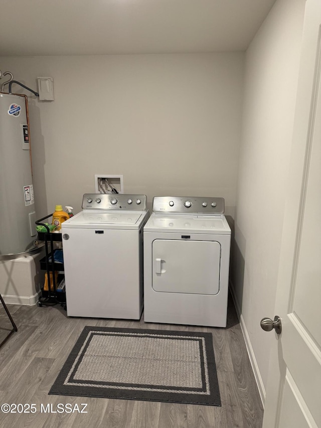laundry area with water heater, separate washer and dryer, wood finished floors, laundry area, and baseboards