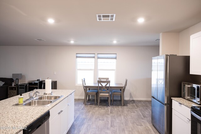 kitchen featuring appliances with stainless steel finishes, light wood-type flooring, a sink, and white cabinetry