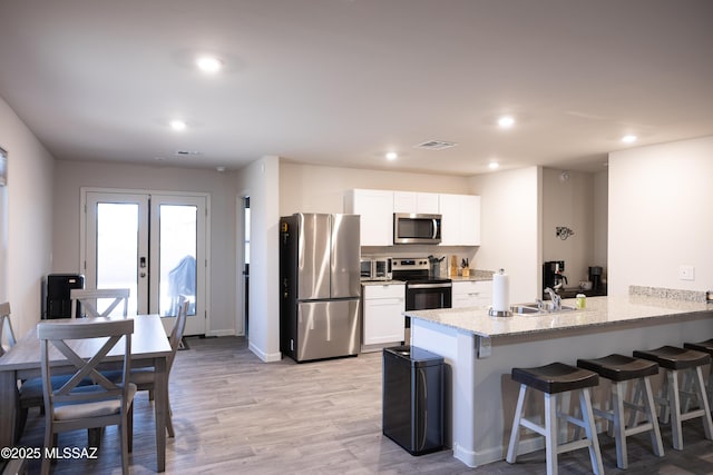 kitchen featuring french doors, a breakfast bar area, stainless steel appliances, visible vents, and a peninsula