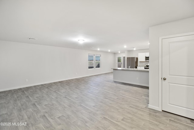 1599 W Cottonwood Bluffs Dr, Benson, AZ 85602 - unfurnished living room with light wood-style floors, recessed lighting, baseboards, and a sink