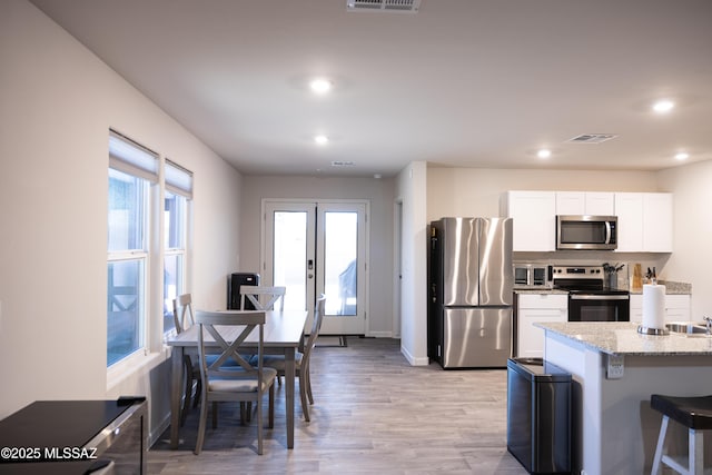 kitchen featuring french doors, appliances with stainless steel finishes, white cabinetry, and a healthy amount of sunlight