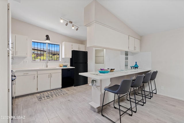 kitchen with sink, a kitchen breakfast bar, kitchen peninsula, white cabinets, and black appliances