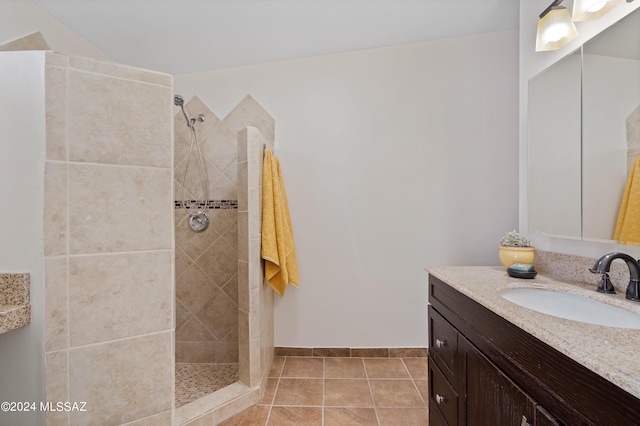 bathroom featuring tiled shower, vanity, and tile patterned flooring