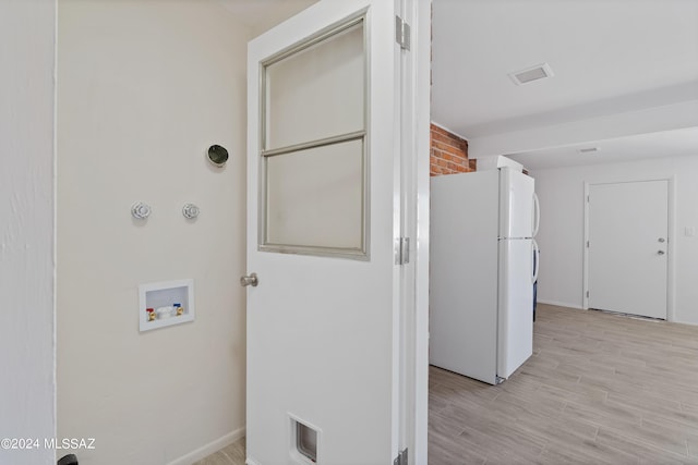 laundry room featuring washer hookup and light hardwood / wood-style flooring