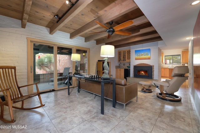 tiled living room featuring ceiling fan, exterior fireplace, wood ceiling, and beam ceiling