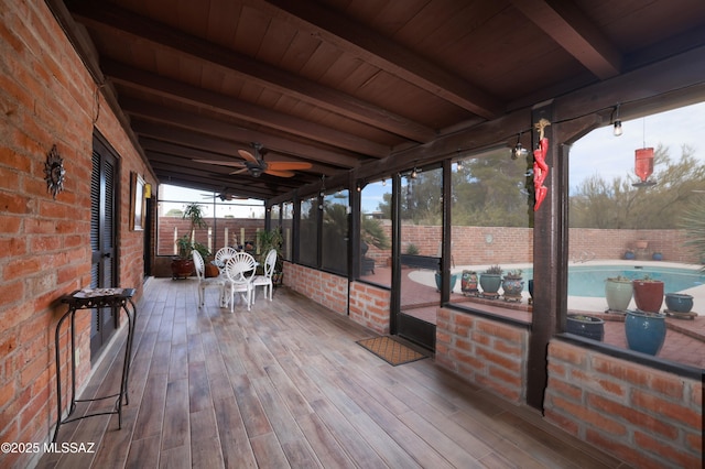 unfurnished sunroom featuring ceiling fan, wooden ceiling, and beam ceiling