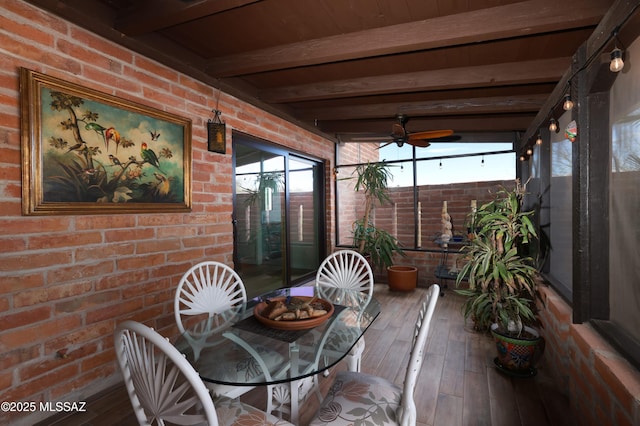 unfurnished sunroom featuring beamed ceiling and ceiling fan