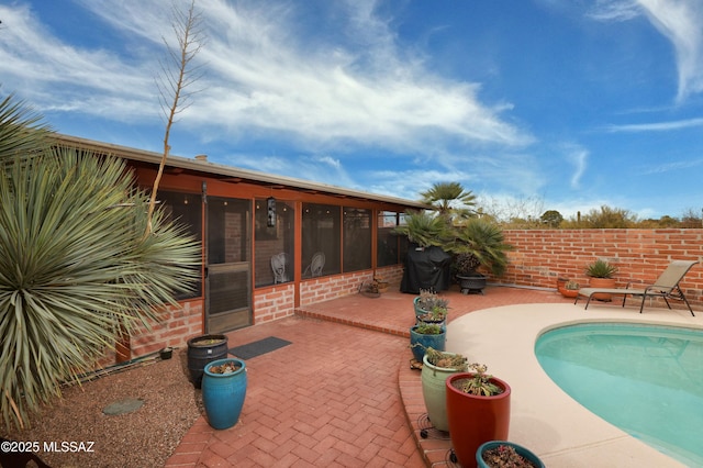 view of pool featuring area for grilling, a patio area, and a sunroom