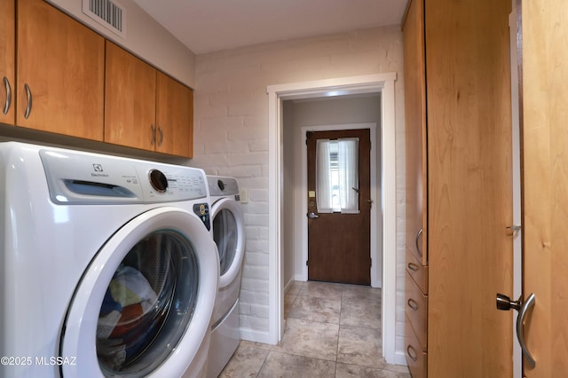 laundry room featuring light tile patterned flooring, cabinets, and washing machine and dryer