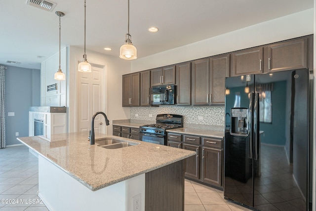 kitchen with an island with sink, light stone countertops, sink, and black appliances