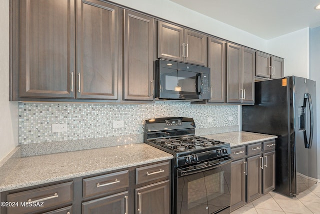 kitchen featuring light tile patterned floors, backsplash, light stone counters, dark brown cabinetry, and black appliances