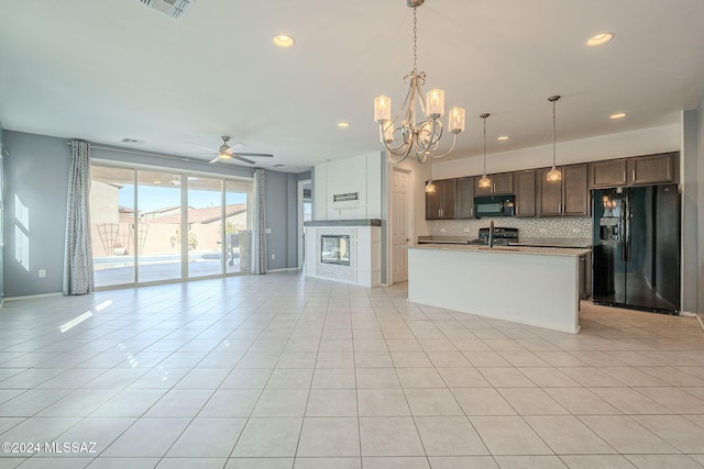 kitchen with black appliances, a center island with sink, dark brown cabinets, pendant lighting, and backsplash