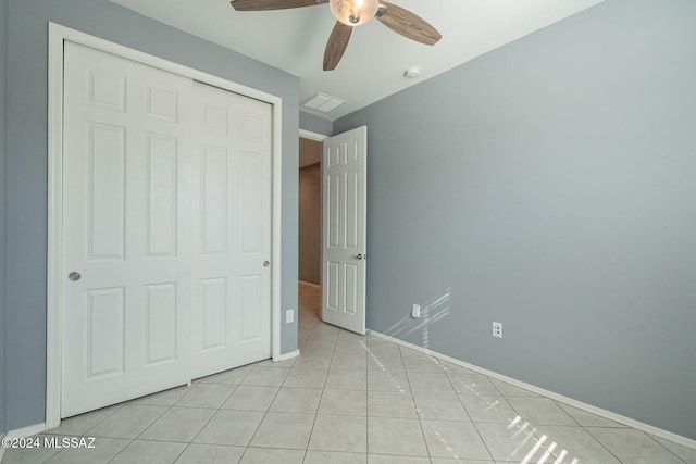 unfurnished bedroom with light tile patterned floors, a closet, and ceiling fan