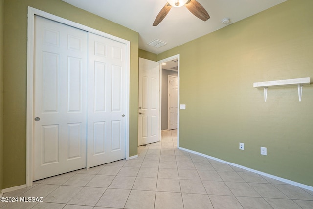 unfurnished bedroom with light tile patterned floors, a closet, and ceiling fan