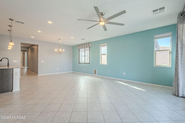 tiled empty room featuring sink and ceiling fan with notable chandelier