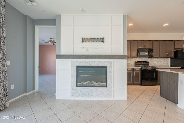 kitchen featuring dark brown cabinetry, light tile patterned floors, tasteful backsplash, and black appliances