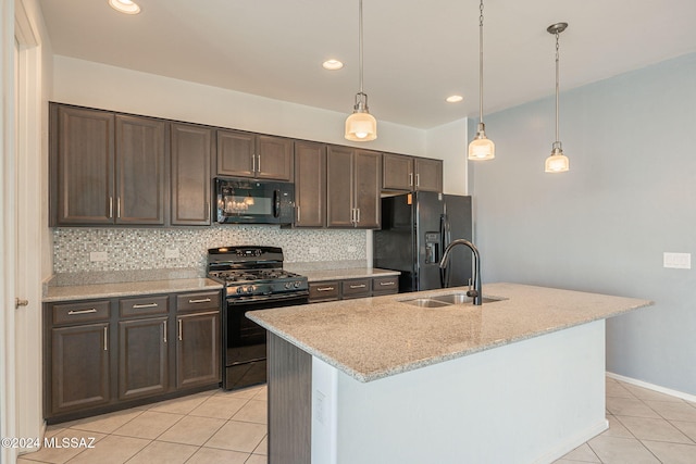 kitchen with pendant lighting, sink, a kitchen island with sink, dark brown cabinetry, and black appliances