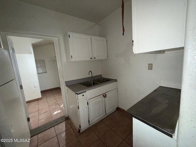 kitchen featuring white fridge, sink, light tile patterned floors, and white cabinets