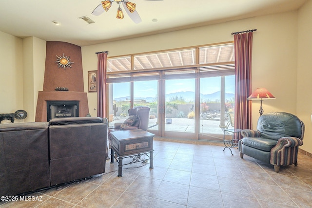 living area with ceiling fan, light tile patterned floors, a mountain view, a fireplace, and visible vents