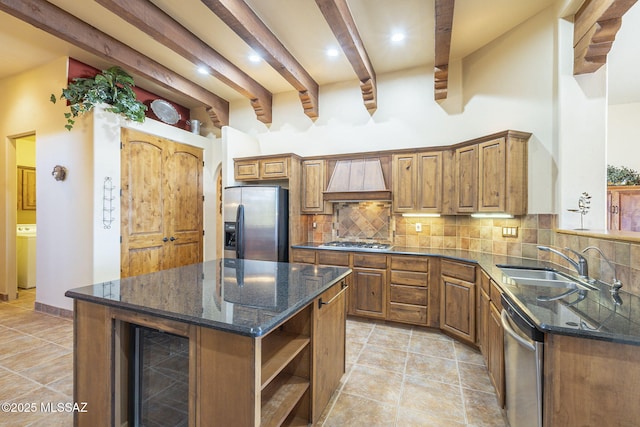 kitchen with stainless steel appliances, tasteful backsplash, a sink, washer / dryer, and beverage cooler