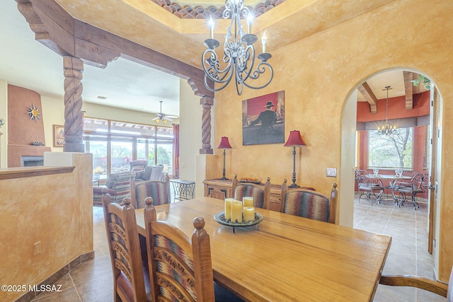 tiled dining area featuring arched walkways and ceiling fan with notable chandelier