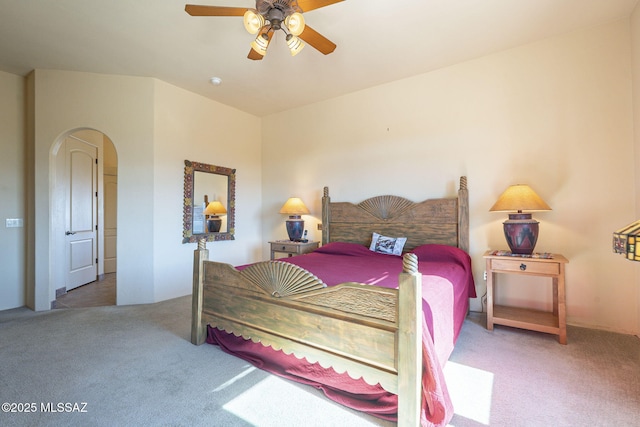 carpeted bedroom featuring a ceiling fan and arched walkways