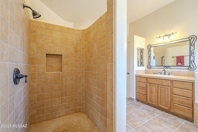 full bathroom featuring a tile shower, vanity, and tile patterned floors