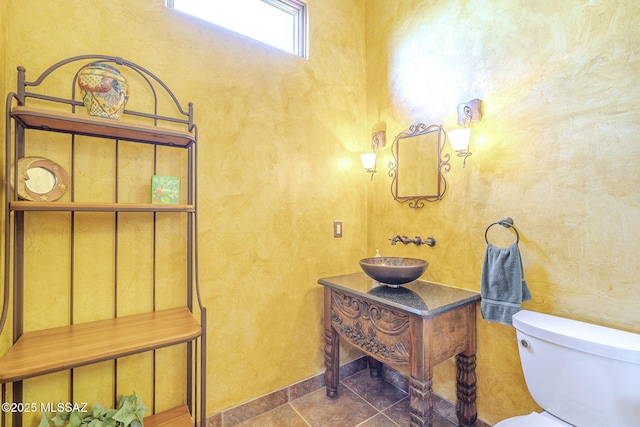 bathroom with toilet, a sink, and tile patterned floors