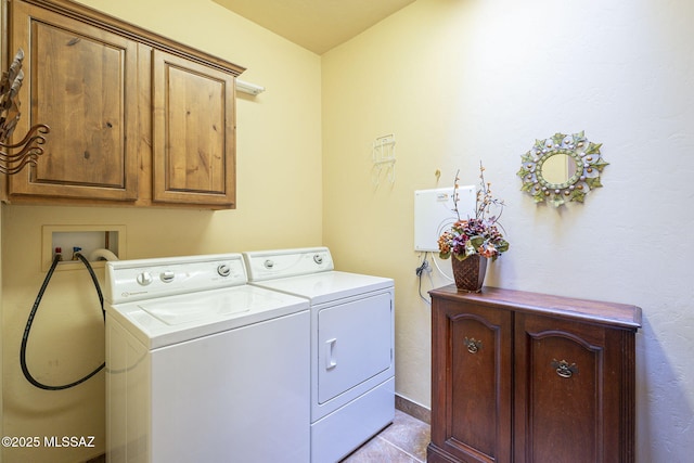 washroom with washing machine and dryer, cabinet space, baseboards, and light tile patterned floors