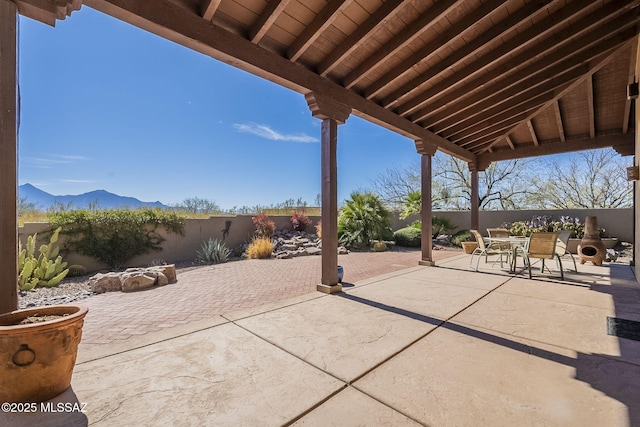 view of patio with outdoor dining space, a fenced backyard, and a mountain view