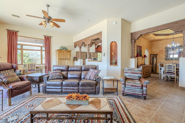 living area featuring ceiling fan with notable chandelier, visible vents, arched walkways, and light tile patterned floors