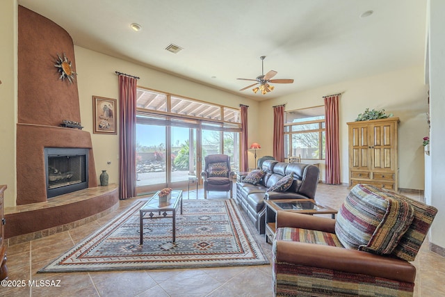 tiled living room featuring ceiling fan, a fireplace, and visible vents