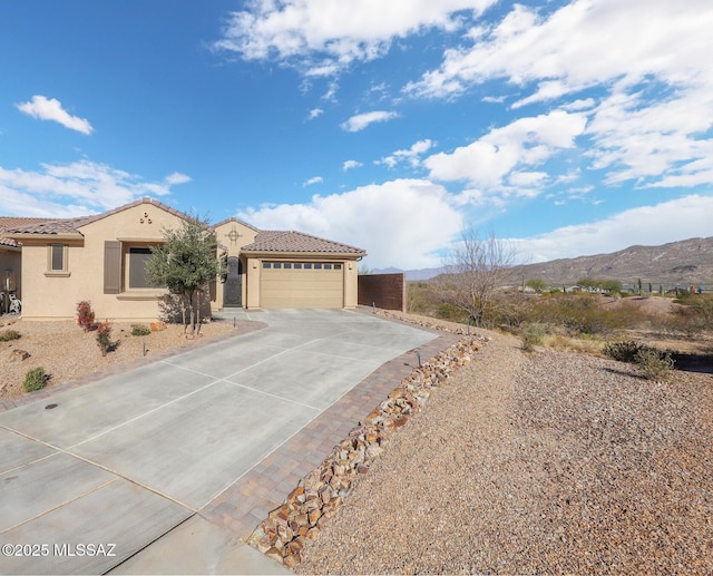 view of front of house featuring driveway, stucco siding, a mountain view, and a tiled roof