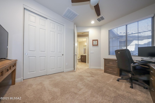 office area featuring baseboards, visible vents, a ceiling fan, and light colored carpet