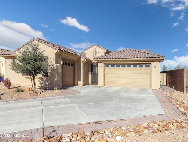 mediterranean / spanish-style house with concrete driveway, a tile roof, an attached garage, and stucco siding