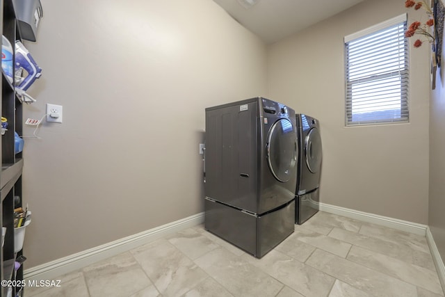 clothes washing area featuring laundry area, washer and clothes dryer, and baseboards