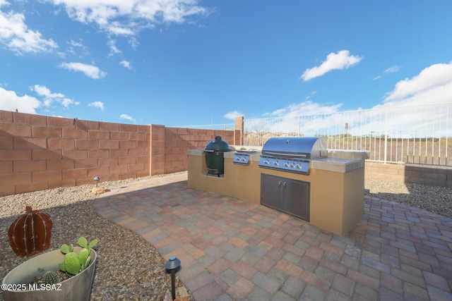 view of patio featuring a fenced backyard, grilling area, and an outdoor kitchen