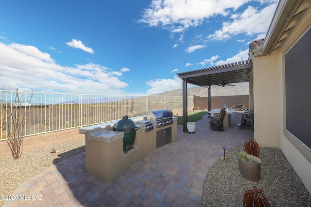 view of patio featuring exterior kitchen, a fenced backyard, a pergola, and area for grilling