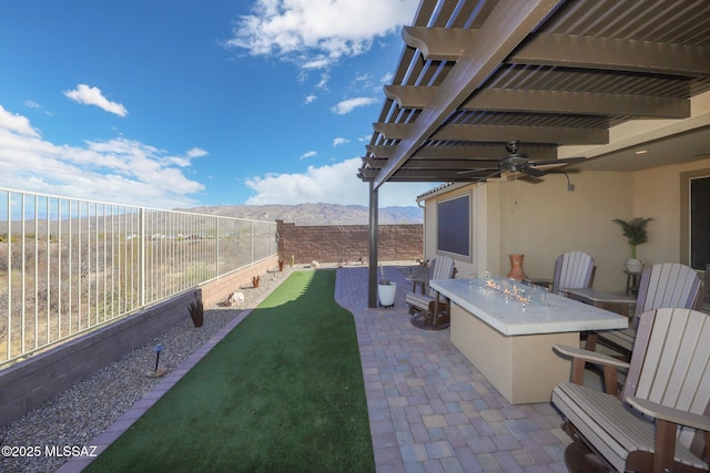 view of patio featuring a fenced backyard, a mountain view, a ceiling fan, outdoor dry bar, and a pergola