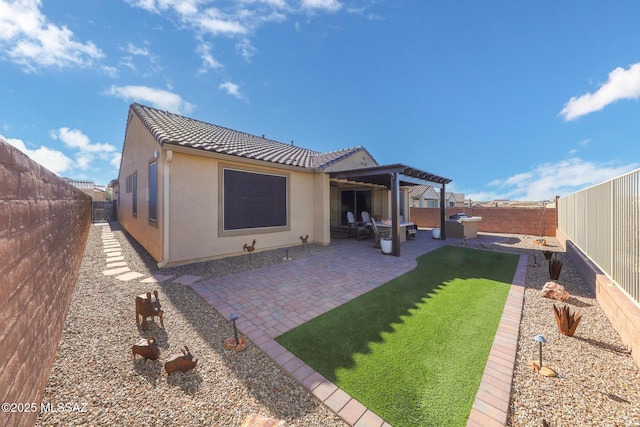 back of house featuring a tiled roof, a patio, a fenced backyard, and stucco siding