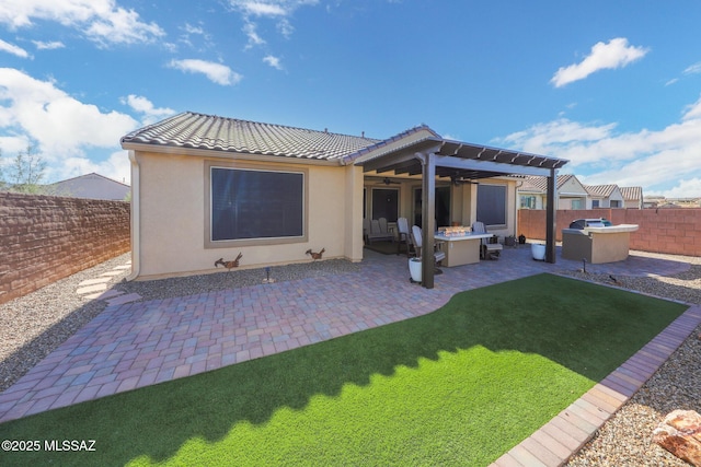 rear view of property featuring ceiling fan, a fenced backyard, a tile roof, stucco siding, and a patio area