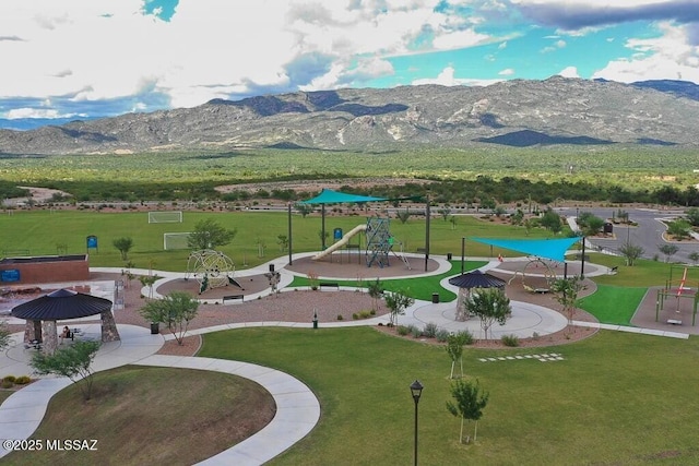 view of home's community featuring a mountain view, playground community, and a yard